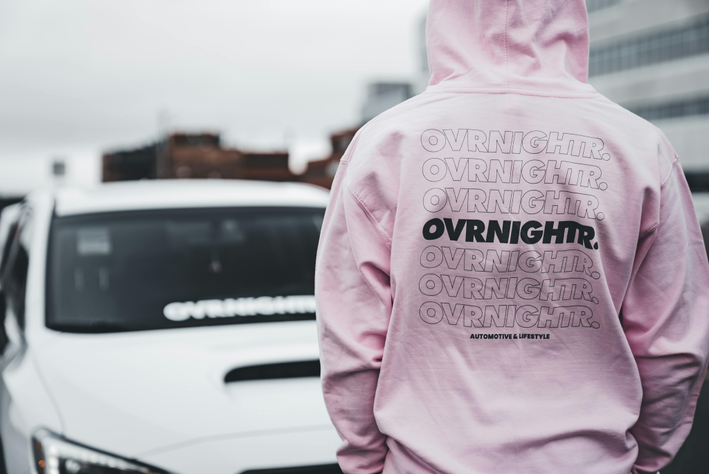 Man walking down the road wearing a pink sweater with hands in his pocket